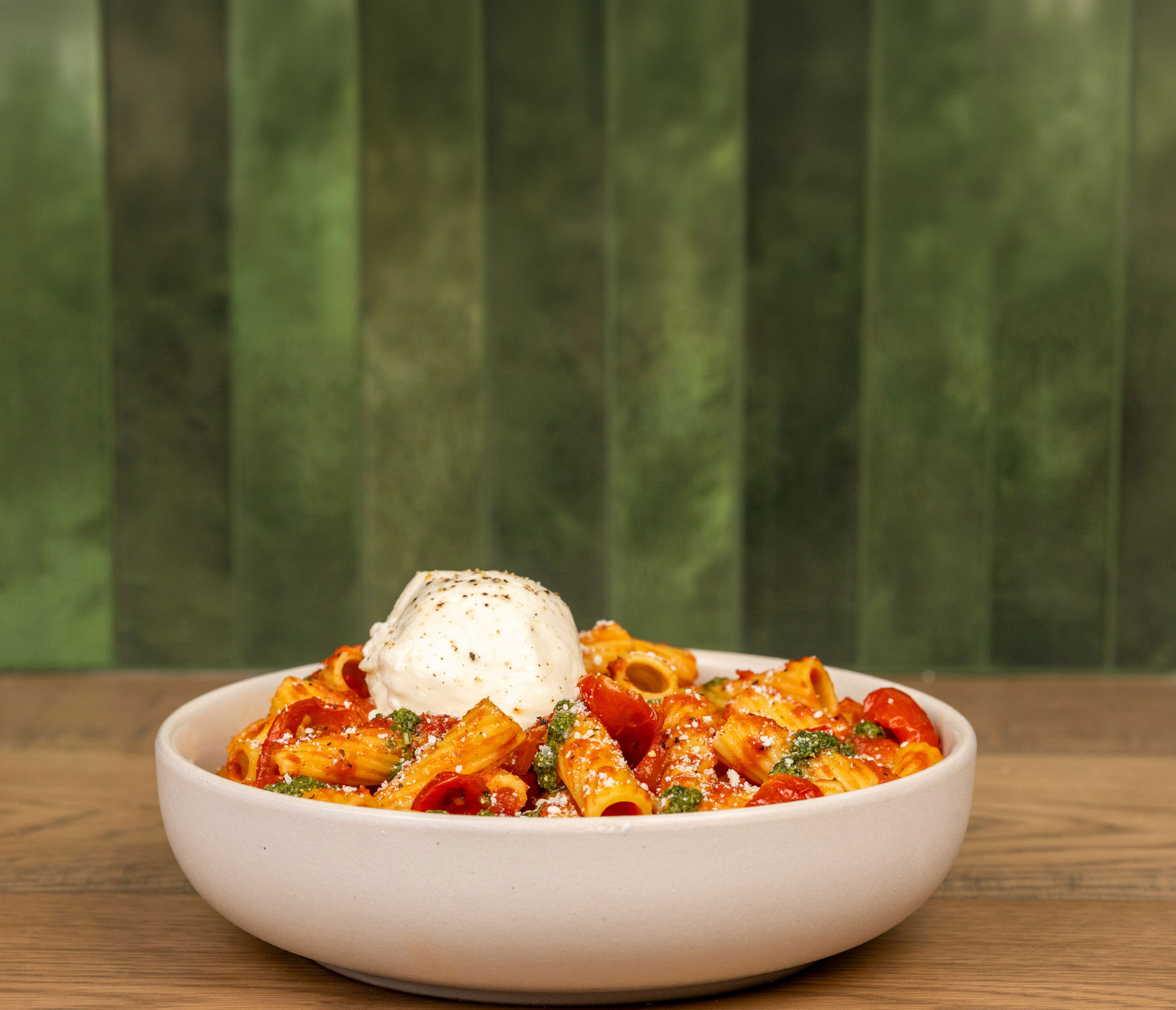 Piada burrata marinara pasta with fresh mozzarella and pesto against signature green tile